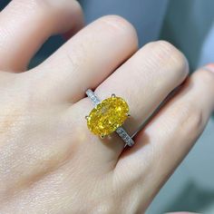 a woman's hand with a yellow diamond ring on it