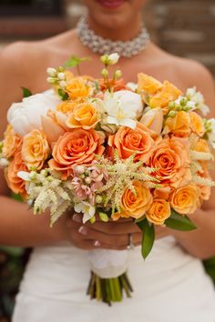 a bride holding a bouquet of orange and white flowers