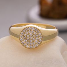 a yellow gold ring with white diamonds on top of a piece of rock next to a plate