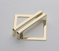 a pair of brass square and rectangle napkin rings on a gray background with space for text