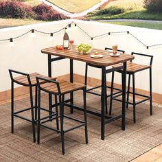 a table with four stools on top of it next to a wall covered in string lights