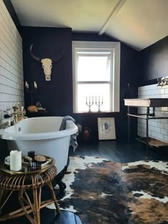 a bathroom with a tub, sink and cow skin rugs on the floor in front of a window