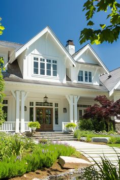 a large white house with lots of windows and landscaping around it's front door