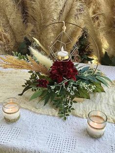 a table topped with candles and flowers on top of a white cloth covered tablecloth