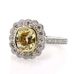 a fancy yellow diamond ring set in white gold with diamonds around the band and center stone