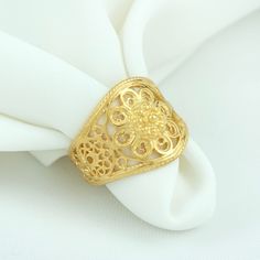 a gold ring sitting on top of a white napkin with a flower design in the center