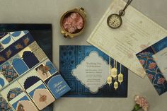 an assortment of wedding stationery items on a table with flowers and a pocket watch