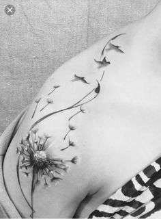 a black and white photo of a woman's stomach with a dandelion tattoo