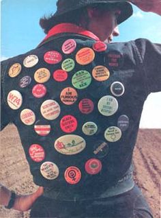 a man wearing a hat and jacket with many different buttons on it's back