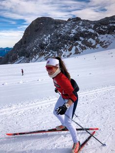 a woman is skiing on the snow with mountains in the background