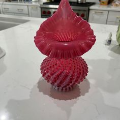 a red vase sitting on top of a white counter