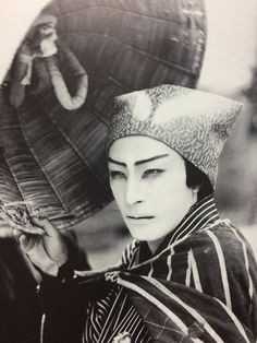 an old photo of a woman in traditional japanese dress holding an umbrella and looking at the camera