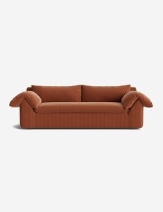 an orange couch with two pillows on the back and one arm folded out to show it's curved shape