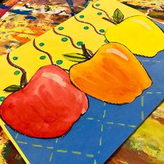 three apples and two oranges are on a blue surface with colorful paintbrushes