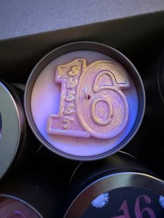 there are six different colored candles with the number sixteen on them in their tins