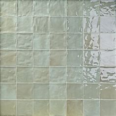 a white tiled wall with water running down it