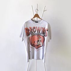 a t - shirt hanging on a clothes rack in front of a white wall with the word browns on it