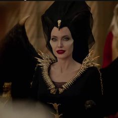 the maleficent character is dressed in black with gold details on her shoulders and chest