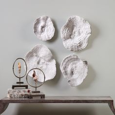 three white plates mounted to the side of a wall next to a book on a table