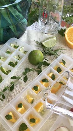 lemons and lime slices are arranged in ice trays on a table with water