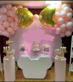 a table topped with lots of white and pink balloons