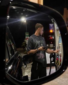 a man is looking at his cell phone in the side mirror of a parked car