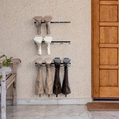 there are several pairs of shoes hanging on the wall next to a bench and potted plant