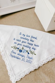 a white handkerchief with blue flowers on it next to a box and some other items