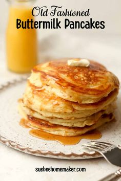 a stack of buttermilk pancakes on a plate next to a glass of orange juice