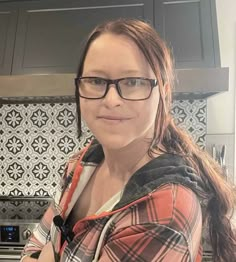 a woman wearing glasses standing in a kitchen