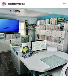 a computer desk with two monitors on it in front of a book shelf filled with books