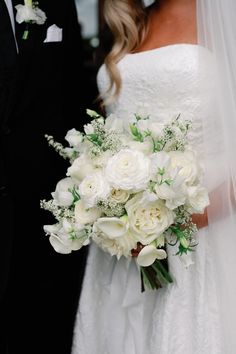 a bride and groom standing next to each other in front of a white wedding bouquet