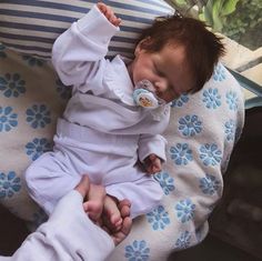 a baby laying on top of a pillow with a pacifier in it's mouth