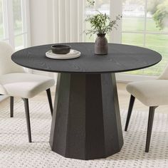 a black table with white chairs and a plant in the vase on top of it