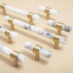 white marble and gold metal handles on a beige background, set of six pieces with one handle