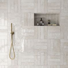 a white tiled bathroom with a gold shower head and hand held shower faucet