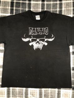 Danzig - Vintage - Classic Hardcore Metal Punk Rock Band T Shirt - Size XXL The shirt shows wear and fading. There are some bleach marks on the front of the shirt. There are holes in the armpits and one sleeve. The graphic shows cracking and fading. Please refer to the photos Distressed Rock T-shirt For Streetwear, Distressed Rock Style T-shirt For Streetwear, Rock Style Distressed T-shirt For Streetwear, Grunge Cotton Tops For Biker Events, Distressed Rock T-shirt For Concerts, Rocker Distressed T-shirt For Concert, Distressed Black Shirt For Streetwear, Rocker Distressed Tops For Streetwear, Black Distressed Shirt For Streetwear