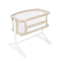 a baby crib that is white and has a beige cover on the top, it's in front of a white background