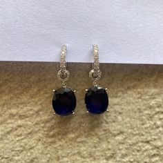 Sapphire Hoop Dangle Earrings featuring vibrant blue stones and adorned with cubic zirconia, these earrings offer a modern twist on classic hoops.  Perfect for bridesmaids or a special gift for your sister, they combine sophistication with contemporary style for any occasion. *𝐏𝐑𝐎𝐃𝐔𝐂𝐓 𝐃𝐄𝐓𝐀𝐈𝐋* * 𝐌𝐚𝐭𝐞𝐫𝐢𝐚𝐥: Brass * 𝐏𝐥𝐚𝐭𝐢𝐧𝐠: White Rhodium Plated * 𝐒𝐭𝐨𝐧𝐞: AAA-quality CZ diamond & Sapphire. *𝐃𝐈𝐌𝐄𝐍𝐒𝐈𝐎𝐍𝐒* * 𝐖𝐞𝐢𝐠𝐡𝐭: 3 gm each * 𝐋𝐞𝐧𝐠𝐭𝐡: 2.8 cm * 𝐖𝐢? Jewelry Classic, Diamond Necklace Designs, Gifts For Your Sister, Blue Stones, Sapphire Earrings, Classic Elegant, American Diamond, Anniversary Gift For Her, Vibrant Blue