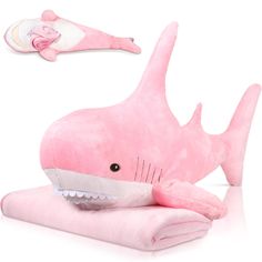 a pink stuffed shark laying on top of a pillow