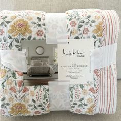 the inside of a bed with white and orange flowers on it, next to a pillow