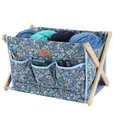 a knitting rack with yarn and crochet hooks in blue floral fabric, on a white background