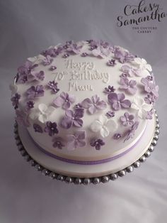 a birthday cake decorated with purple and white flowers