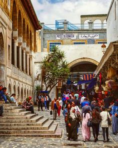 many people are walking up and down the stairs in an old city area with stone steps