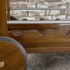 an old fashioned wooden cart with wheels on the ground next to a brick wall and window