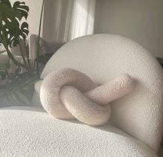 a white chair with a knot on it's back in front of a potted plant