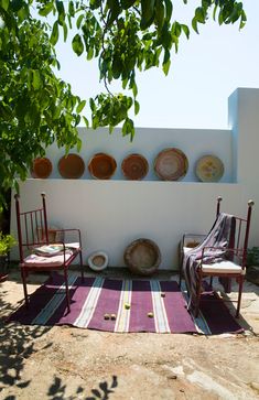 two chairs sitting in front of a wall with plates on it