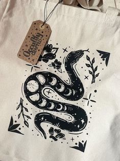 a white bag with a black snake on it and a tag hanging from the front