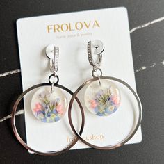 a pair of earrings with flowers on them sitting on top of a card next to a package