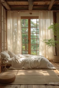 a bed sitting under a window next to a wooden table with a potted plant on top of it